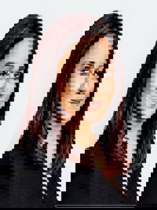 A headshot of Ameeta, a young professional brunette woman in a business suit